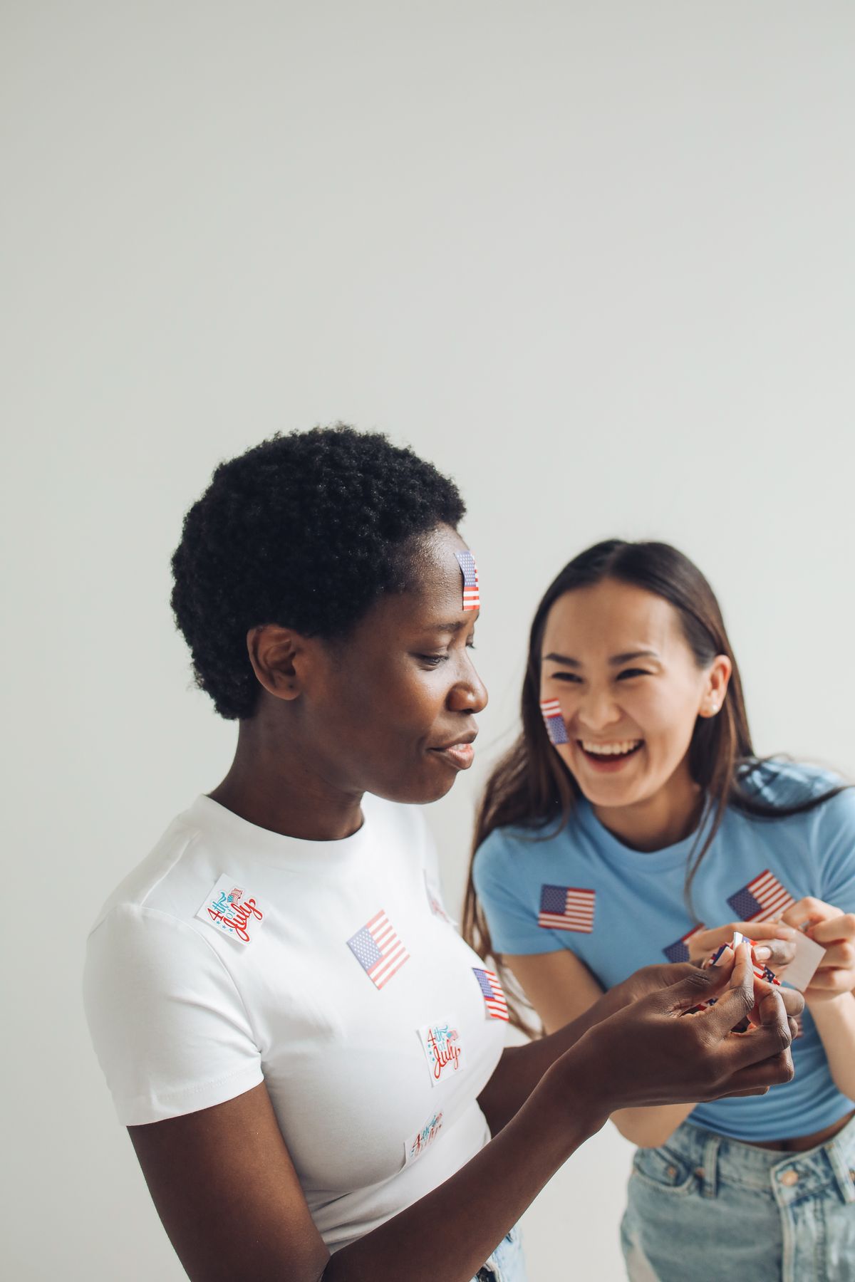 Two friends in flag-print tees laughing together
