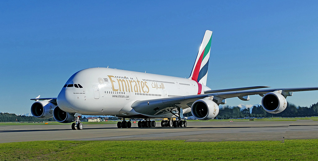 A large four engine airliner taxiing at an airport under a clear sky