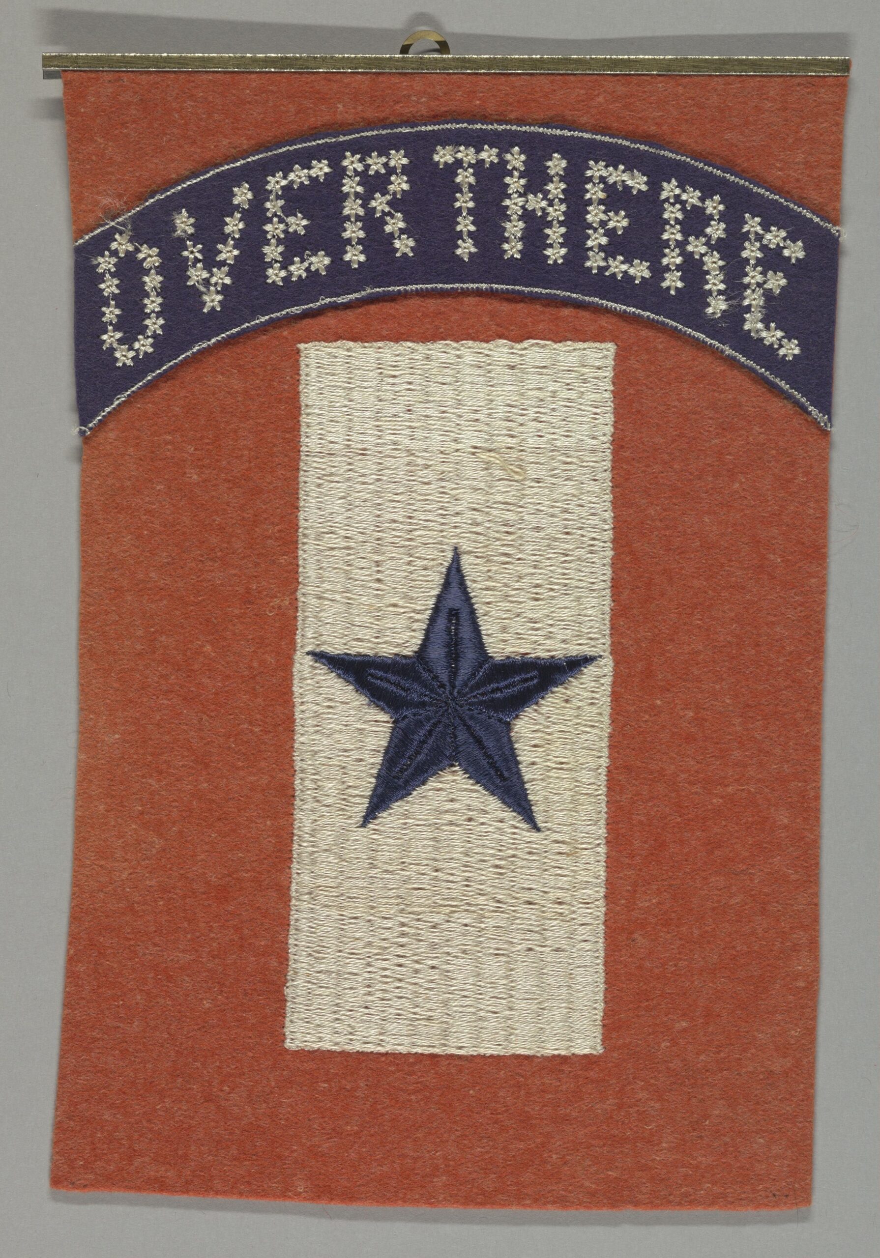 An antique service banner embroidered with the words Over There above a single blue star