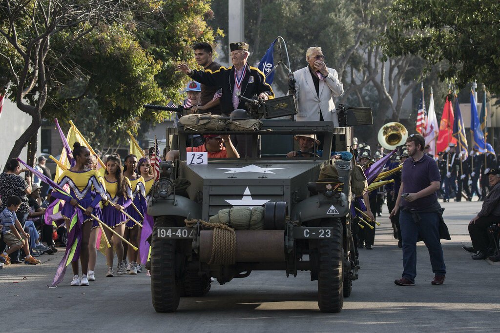 A vintage military vehicle carrying veterans in a Veterans Day parade