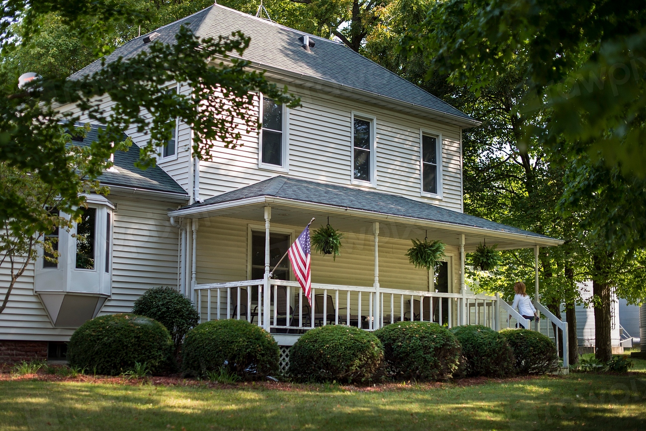 A white farmhouse with an American flag hanging from the porch