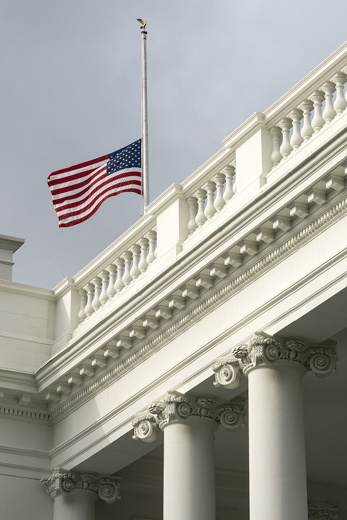 The United States flag flying at half staff above a white colonnade